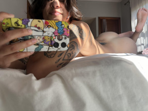 Nackte Frau mit Tattoos und Smartphone